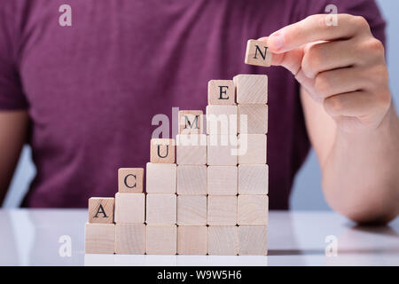 A Person's Hand Placing Last Alphabet Of Word Acumen On Stacked Block Stock Photo