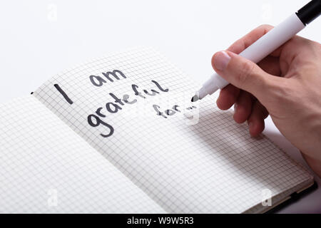 Close-up Of A Person Writing I Am Grateful For Text In Notebook With Black Marker Stock Photo