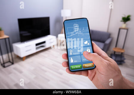 Man Using Smart Home Application On Mobile Phone Stock Photo