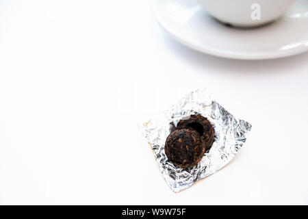 Chinese PU-erh tea in the shape of a ball of old fragrant tea and dry cylindrical bricks. Fragrant black PU-erh tea. Healthy drink. Stock Photo
