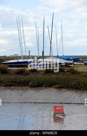Partially obscured sign 'Danger: Soft Mud'  at Brancaster Staithe, on the north Norfolk coast, at low tide Stock Photo