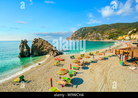 Chairs and umbrellas fill the Spiaggia di Fegina, the wide sandy beach in front of the old section of the village of Monterosso al Mare, Italy Stock Photo