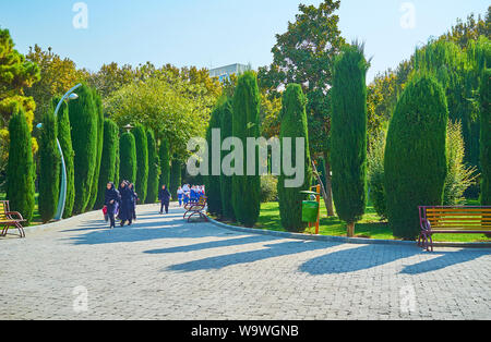 TEHRAN, IRAN - OCTOBER 25, 2017: The group of little Iranian schoolgirls, dressed in uniforms and hijabs, runs and plays during excursion to Laleh Par Stock Photo