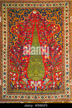 TEHRAN, IRAN - OCTOBER 25, 2017: The medieval Persian garden carpet with colorful floral and foliate patterns, flowers and cypress tree, symbolizing e Stock Photo