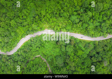 Aerial view of countryside road passing through the tropical rainforest and mountain in SouthEast Asia. Stock Photo
