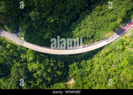 Aerial view of countryside road passing through the tropical rainforest and mountain in SouthEast Asia. Stock Photo