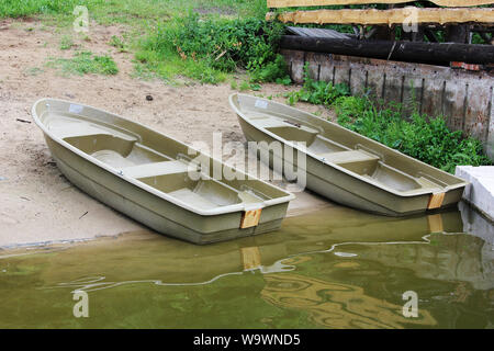 Plastic fishing boats on the bank of the lake in summer sunny day