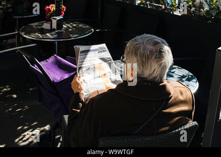 Barcelona, Spain - Nov 14, 2017: rear view from above of senior man reading Spanish newspaper while drinking a coffee at the outdoor terrace in central Barcelona Stock Photo