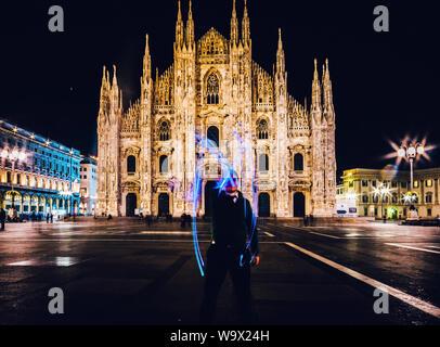 Man using light painting long exposure draws an M letter in front of the Milan Cathedral, Milan, Italy. Stock Photo
