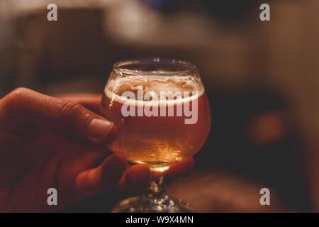 Closeup shot of a snifter beer glass filled with beer to the brim Stock Photo