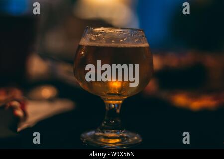 Closeup shot of a snifter beer glass filled with beer to the brim Stock Photo