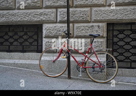 Montreal, Quebec / Canada - July 25, 2019: Red bike locked up to a pole on the sidewalk Stock Photo