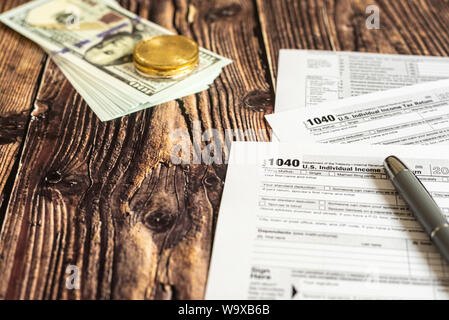 Dollar bills on a table in which the 1040 American tax payment form is filled out. Stock Photo