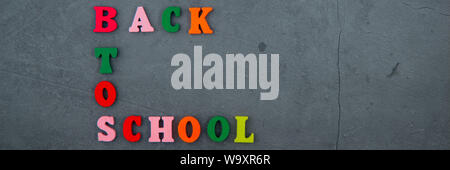 The multicolored back to school word is made of wooden letters on a grey plastered wall background Stock Photo