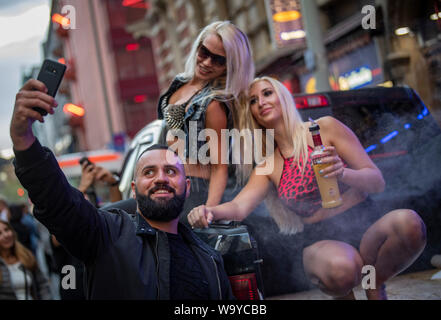 15 August 2019, Hessen, Frankfurt/Main: Yussuf from Iraq uses the opportunity for a selfie with two dancers performing during the station quarter night. Every year the Frankfurters celebrate the railway station district with the street festival. (to dpa 'Frankfurt celebrates station quarter with big street festival') Photo: Boris Roessler/dpa Stock Photo