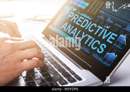 Close-up Of Businessman Working On Laptop Doing Predictive Analytics In Office Stock Photo