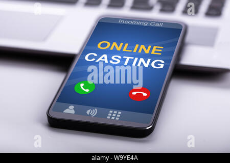 Smartphone With Online Casting Text Receiving Incoming Call On Display Placed Over Laptop Stock Photo