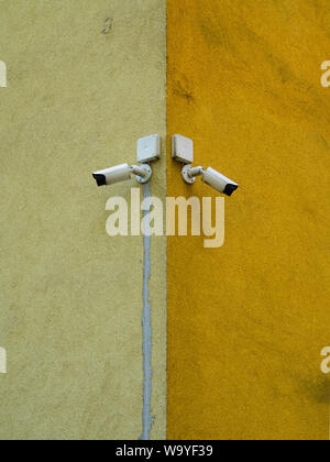 Two cameras of the monitoring system. Cameras placed on the corner of the building. Control and monitoring system. Bright, dirty background. Stock Photo