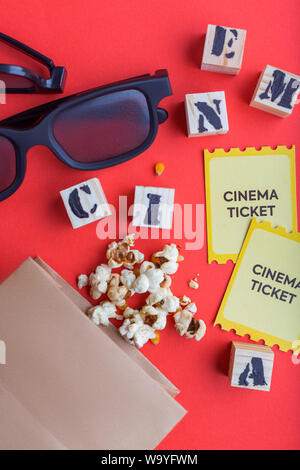 craft bag with popcorn 3d cinema glasses tickets wooden cubes with text on red background creative flatlay Stock Photo