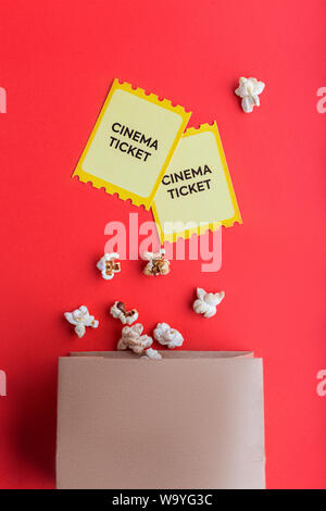 craft bag with popcorn and two yellow cinema tickets on red background flatlay  Stock Photo