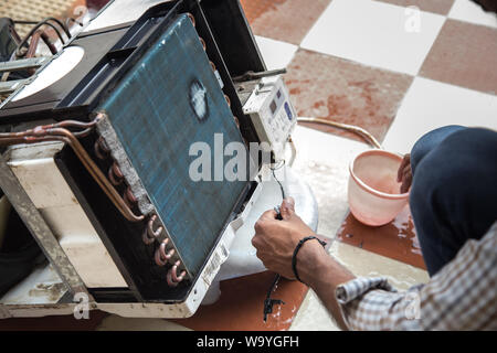 Worker cleaning window air conditioner by water for clean a dust on it in customer home when maintenance service. Breath, repair. Stock Photo