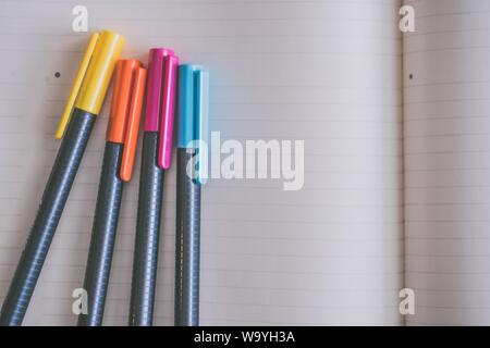 Closeup shot of colorful markers on an opened textbook Stock Photo