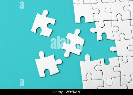 Unfinished white puzzle pieces on blue background Stock Photo