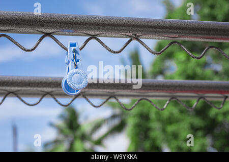 Plastic clothespin on a clothesline and in the daytime sky. Stock Photo