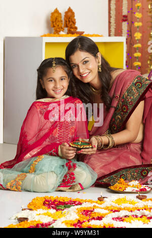 Woman with her daughter holding oil lamp Stock Photo
