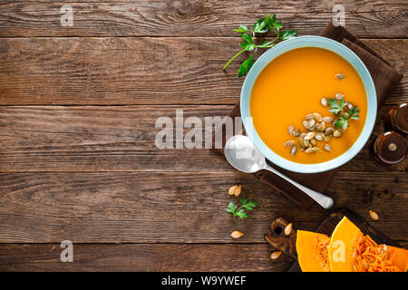 Pumpkin soup. Vegetarian soup with pumpkin seeds in bowl on wooden table, top view Stock Photo