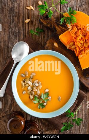 Pumpkin soup. Vegetarian soup with pumpkin seeds in bowl on wooden table, top view Stock Photo