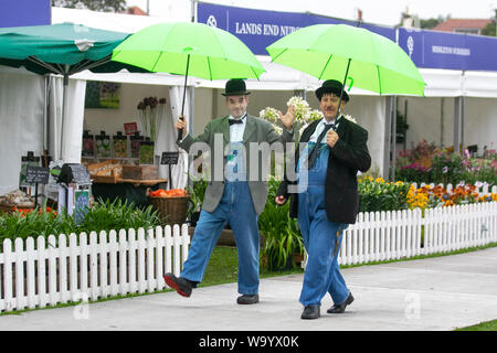 Southport, Merseyside. UK Weather. 16th August, 2019. Washout anticipated as heavy rain deluges the Southport Flower Show. Laurel and Hardy lookalikes endure heavy persistant rain throughout the morning. Rather windy throughout the day as attendances are affected by the adverse weather. Stock Photo