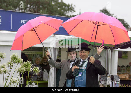 Southport, Merseyside. UK Weather. 16th August, 2019. Washout anticipated as heavy rain deluges the Southport Flower Show. Laurel and Hardy lookalikes endure heavy persistant rain throughout the morning. Rather windy throughout the day as attendances are affected by the adverse weather. Stock Photo