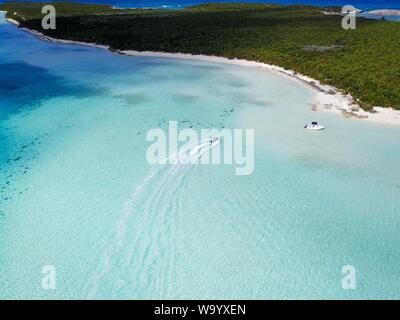 Aerial shot of boats in the ocean near a green island in Exuma Stock Photo