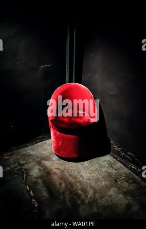 Vertical shot of a red suede chair in the corner of black walls Stock Photo