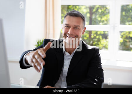 Portrait Of Confident Businessman Offering Handshake In Office Stock Photo