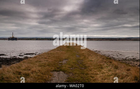 An oil rig shelters in the Cromarty Firth offshore from a disused pier near Alness in the Highlands of Scotland. Stock Photo