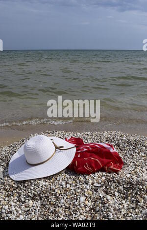 Vintage summer straw beach hat and pareo on the seashore. Accessories for relaxing on the beach. Summer lifestyle. Vacation mood. Stock Photo