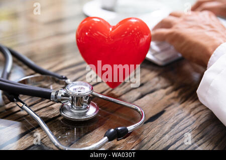 Red Heart With In Front Of Doctor Working On Computer Stock Photo