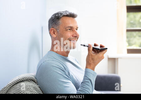 Close-up Of A Beard Man Using Voice Recognition Function On Mobile Phone Against White Background Stock Photo
