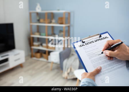 Close-up Of A Man's Hand Filling Real Estate Appraisal Form With Pen Stock Photo