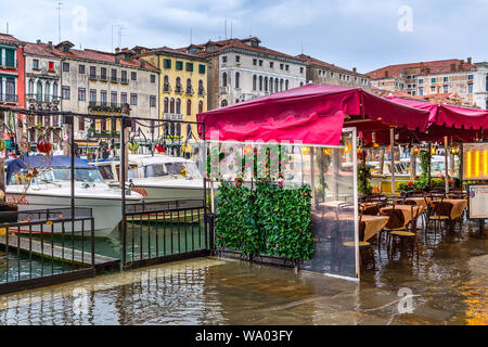 Venice, Italy - November 10, 2014: Flood in Venice, cafe restaurant tables and chairs in high water, colorful houses and boats Stock Photo