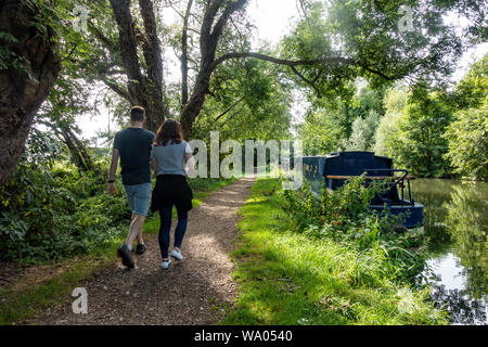 A couple out for a stroll down a path along the side of The River Kennet at Reading in Berkshire, UK Stock Photo