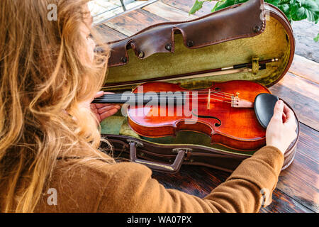 Womans hands holds old violin in case closeup Stock Photo