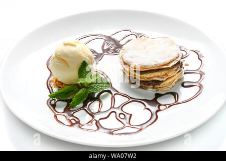 French dessert millefeuille, with chocolate syrup and vanilla ice cream on white background. Served with mint leaves on a white plate. Stock Photo