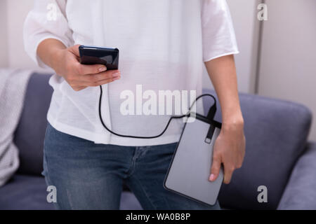 Mid-section Of Woman Using External Hard Disk For Data Transfer Stock Photo