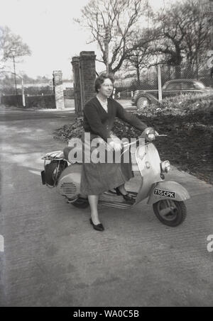 1960s, historical, England and a lady in a skirt sitting outside on a vespa scooter, an Italian made motor scooter manufactured in Tuscany by Piaggio, who were founded in 1946. Stock Photo