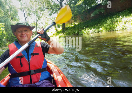 the man in the lifejacket, the man with the paddle, smiling man in kayak, Angrapa river, Kaliningrad region, Russia, Eastern Europe, 15 June 2019 Stock Photo