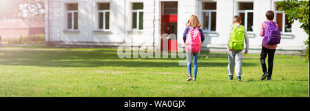 Children with rucksacks standing in the park near school Stock Photo