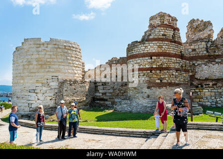 Nessebar, Bulgaria July 15, 2019. A crowd of people walking around the ancient city of Nessebar in Bulgaria.Ruins of fortifications at the entrance. Stock Photo